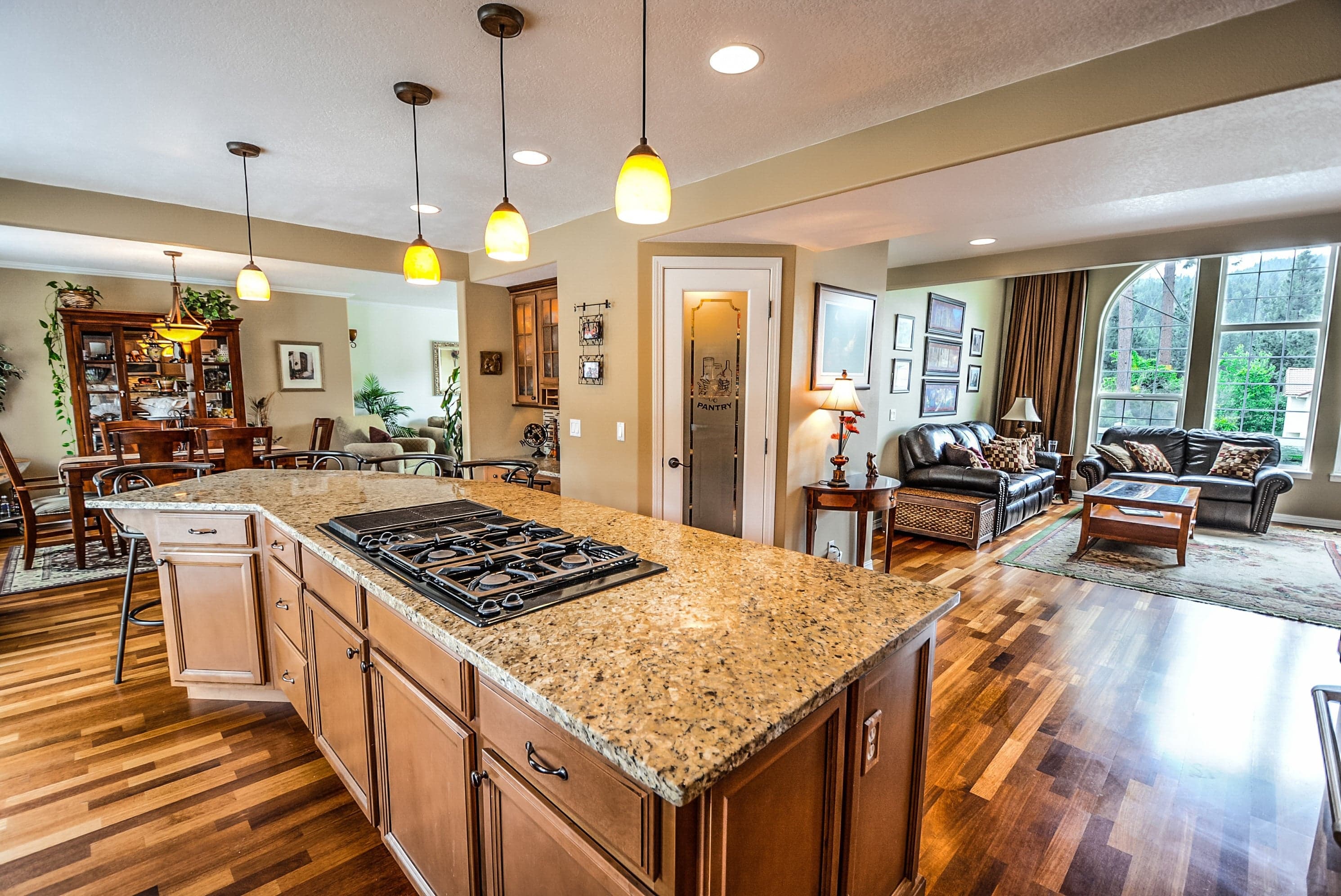 Before: original kitchen photo with granite island, hardwired pendant lights, and cluttered furniture